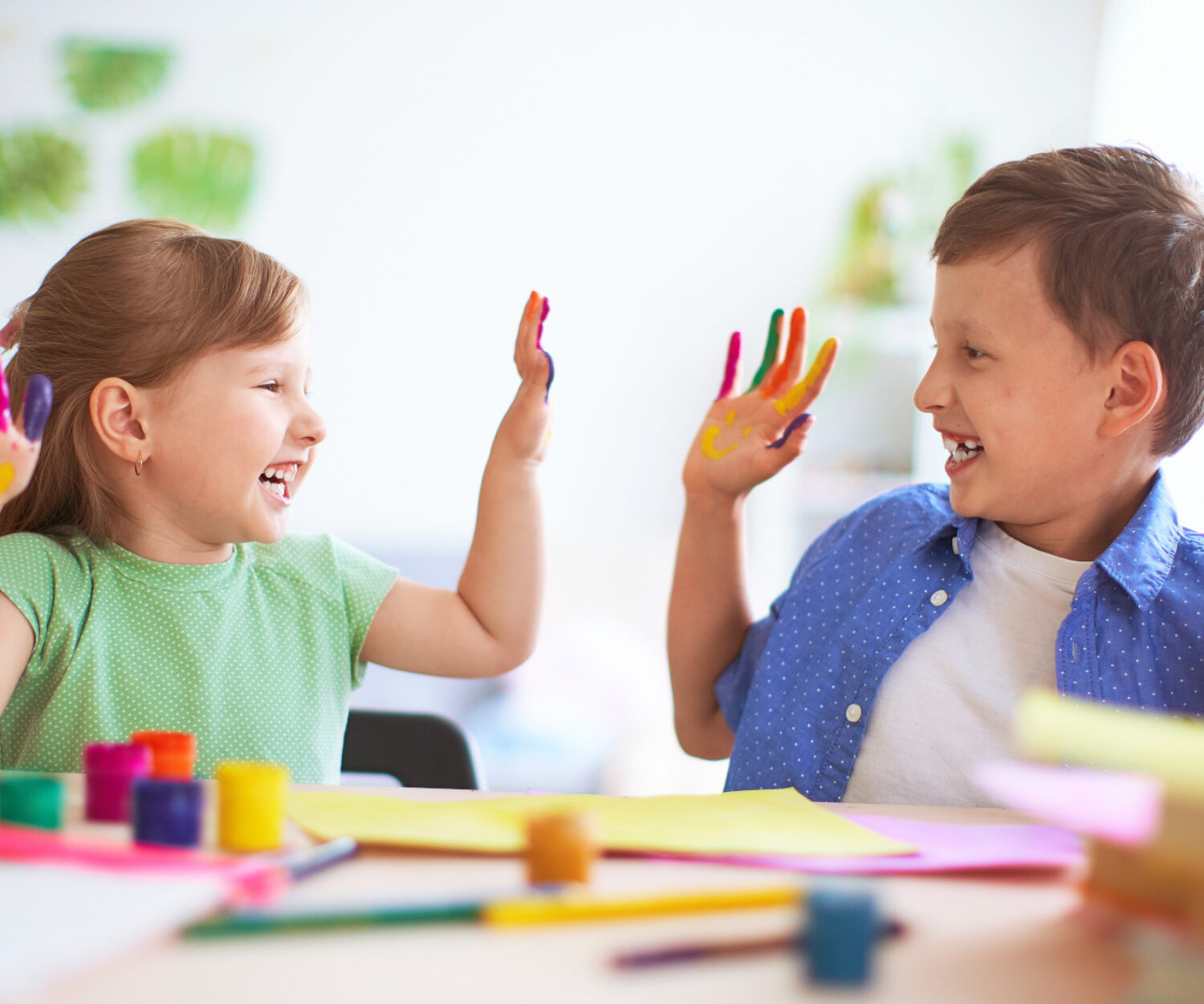 funny kids show their palms the painted paint. creative classes fine arts. two children a boy and a girl laugh. selective focusing on the palm. happy kids in drawing school